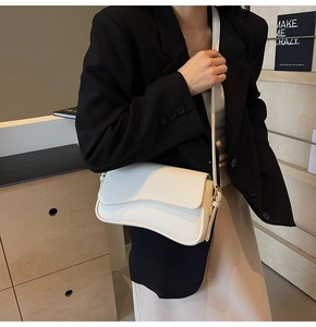 Macro detail of the wave-shaped flap and lychee texture on the ivory shoulder bag