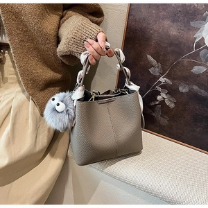 Taupe lychee leather bucket bag with patterned scarf handle and plush monster charm