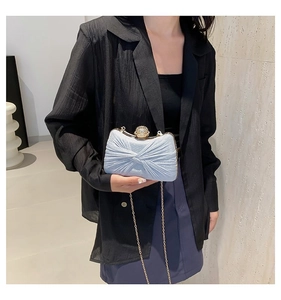 Détail d'une pochette de soirée bleu clair avec tissu plissé et fermoir boule en cristal