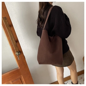 Detail view of large dark brown canvas tote bag draped on model for fall casual style