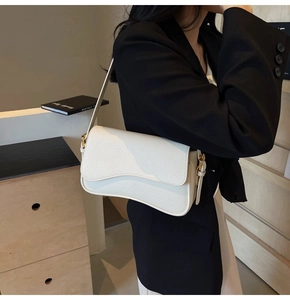 Detail of white lychee texture leather shoulder bag with wavy flap and gold hardware