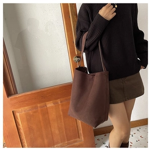 Brown canvas shoulder bucket bag worn by model in a minimalist lifestyle setting