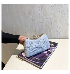 Vue macro de la pochette bleu clair à paillettes avec design plissé et fermoir strass