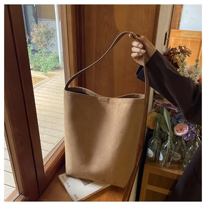 Close-up of camel suede tote bag with a minimalist large capacity bucket structure