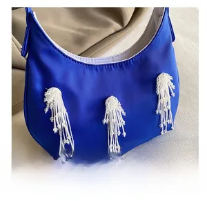 Dettaglio della borsa hobo blu reale con nappe di perline bianche e cuciture
