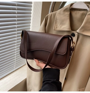 Detail of dark brown lychee texture leather shoulder bag with wavy flap design