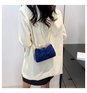 Sac de soirée en velours bleu roi avec chaîne dorée porté par un mannequin