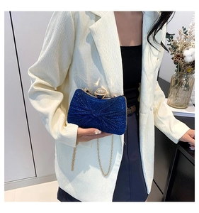 Détail de la pochette de soirée à paillettes bleu marine avec nœud et chaîne dorée