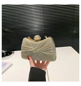 Détail d'une pochette de soirée champagne avec texture plissée et fermoir cristal