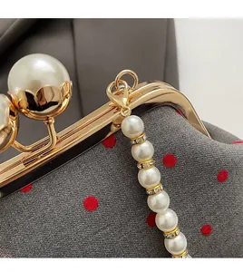 Detail of grey polka dot evening bag with gold frame and large pearl clasp decoration