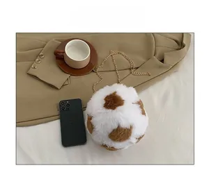 Detailed view of spherical cow-print plush bag with gold chain strap on white table