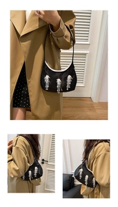 Dettaglio della borsa in raso nero con frange di perline bianche e tracolla sottile elegante