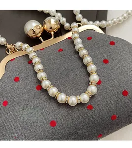 Close-up of vintage polka dot clutch bag with pearl chain handle and gold ball clasp