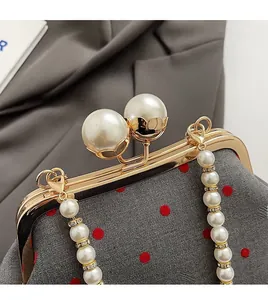 Detailed view of grey polka dot evening bag with large pearl clasp and pearl strap
