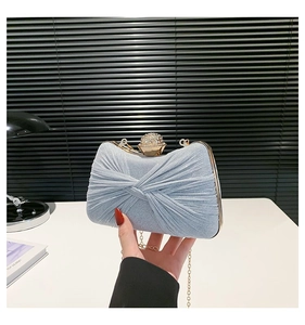 Détail d'une pochette de soirée plissée bleu clair avec fermoir en strass et chaîne