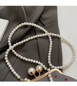Detail of white faux pearl strap with gold metal clasps on a polka dot evening bag