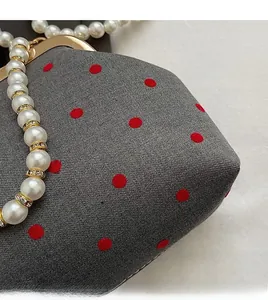 Detailed macro view of the grey fabric bag with red polka dots and pearl bead handle