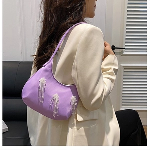 Dettaglio della borsa in nylon viola con nappe di perline bianche e trama setosa