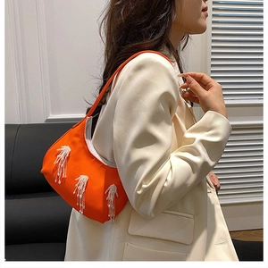 Dettaglio borsa a mezzaluna in nylon arancione con eleganti frange di paillettes bianche