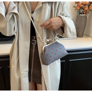 Detail of grey polka dot evening bag with metal clasp and elegant white pearl chain strap