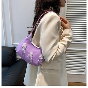 Dettaglio della borsa hobo lilla con eleganti decorazioni di frange in perline bianche