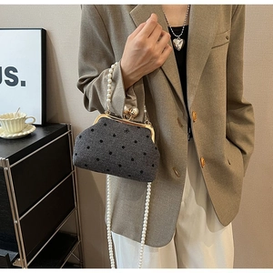Detail view of retro polka dot handbag featuring pearl handle and herringbone fabric