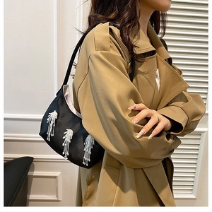 Borsa a spalla in nylon nero con frange di perline bianche su un trench color kaki