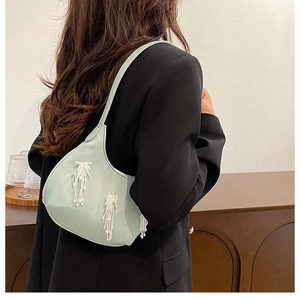 Elegante borsa a mezzaluna verde menta con nappe di perline bianche in un set lifestyle