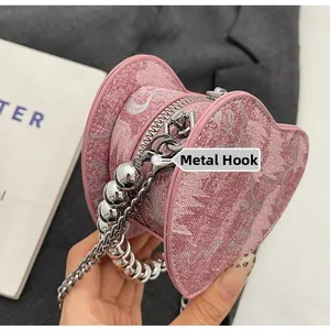 Detail of pink heart-shaped jacquard mini bag with silver chain and bead strap