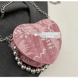 Detail of pink heart-shaped bag with floral embroidery and metallic bead fringe