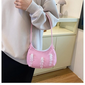 Dettaglio borsa hobo rosa in nylon con nappe di perline bianche e tracolla sottile