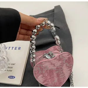 Pink heart-shaped nylon bag featuring large silver bead handle and metal chain strap