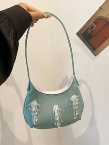 Dettaglio borsa a mezzaluna verde salvia con frange di perline e finitura in pelle