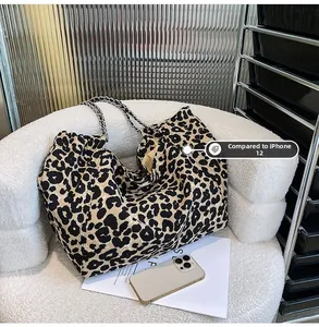 Detailed comparison of leopard print tote bag size with an iPhone 12 on a chair