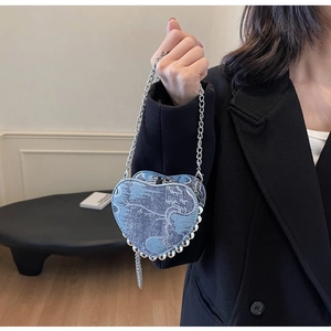 Detail of heart-shaped denim handbag with silver bead trim and metal chain strap