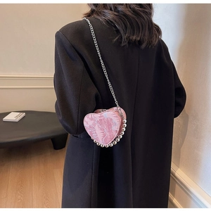 Pink heart-shaped nylon bag with silver bead trim and metallic chain on a model