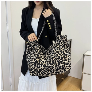 Detail of a large leopard print tote bag with silver chain strap on a female model