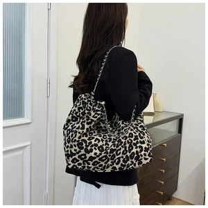 Detailed back view of a leopard print tote bag with silver chain straps worn by a model