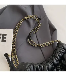 Close-up of black pleated cloud bag with elegant gold and black chain strap detail