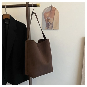 Minimalist deep brown oversized tote bag in faux suede hanging on a vintage wooden rack