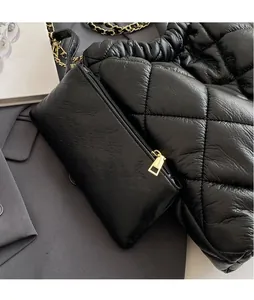 Detail of black quilted shoulder bag with matching mini pouch and gold chain strap