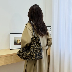 Detail of leopard print tote bag with chain strap shown on a camel trench coat