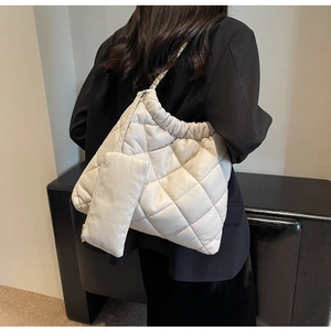 Detail of white quilted crossbody bag with a hanging coin purse and metal chain strap