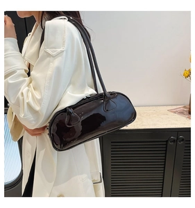 Gros plan d'un sac à bandoulière en cuir verni marron foncé brillant avec fermoir métal