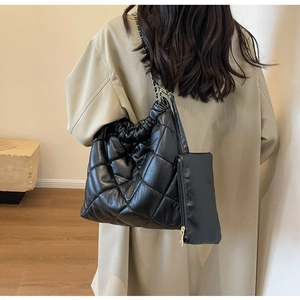 Detailed view of black quilted crossbody bag with gold chain and small zipper pouch