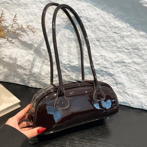 Détail du sac Boston en cuir verni marron foncé avec texture brillante et zip argenté