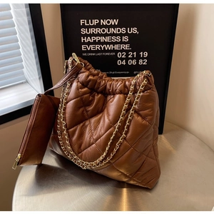 Detail of dark brown quilted crossbody bag with gold chain and matching coin purse charm