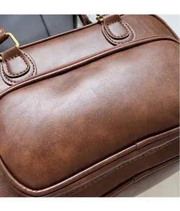 Close-up of brown litchi grain faux leather handbag with gold metal hardware buckle