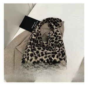 Sac fourre-tout en peluche imprimé léopard posé sur un tissu blanc avec un trench-coat