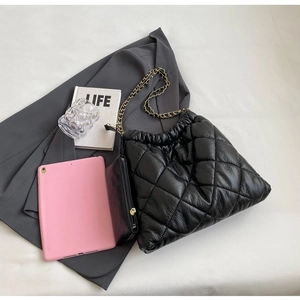 Detail of black quilted chain bag with puff texture and matching mini pouch accessory